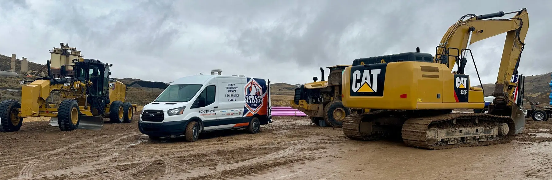 On Site Lube service van on a jobsite between a Cat excavator and a motor grader