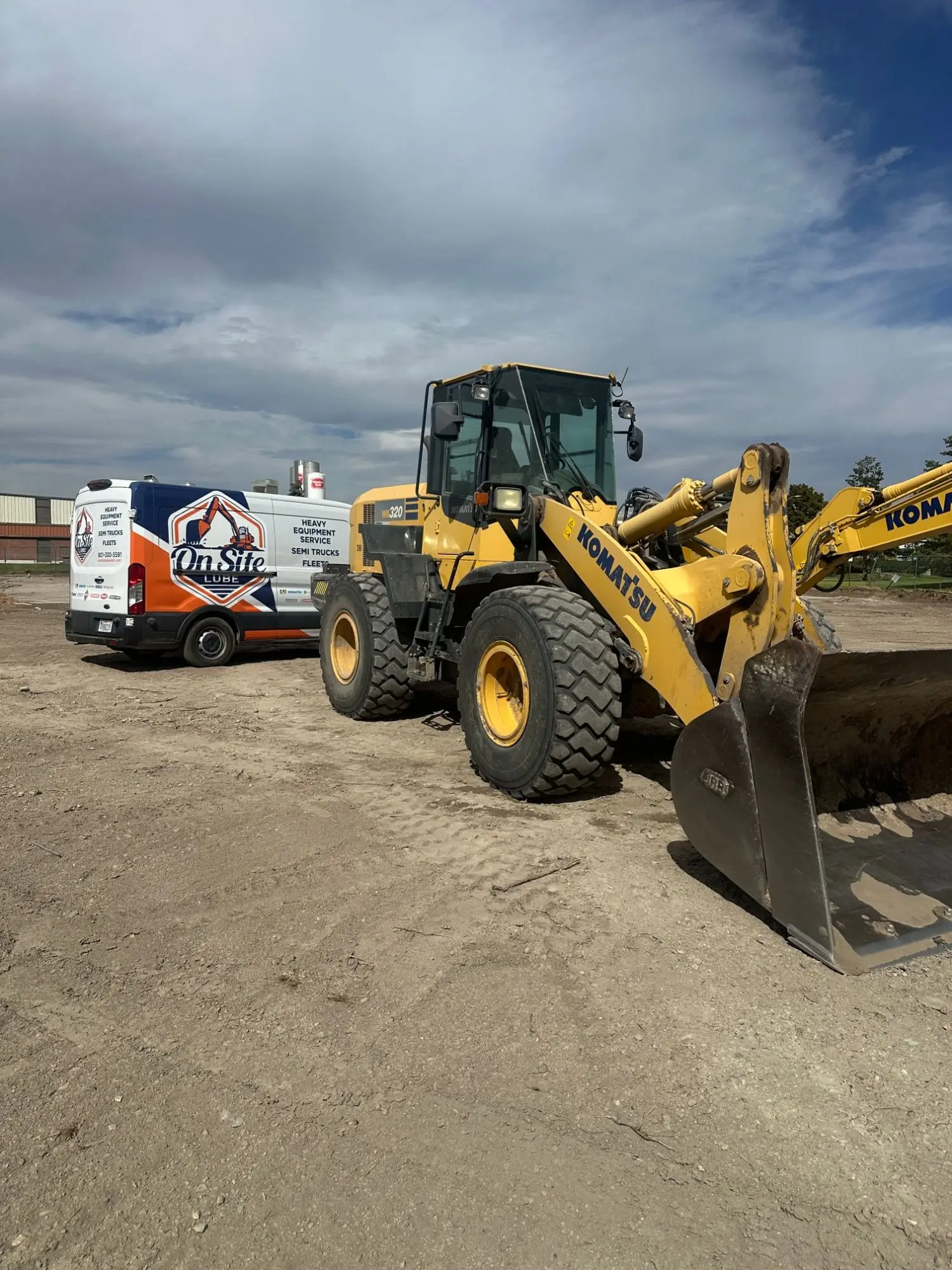On Site Lube service van parked on a jobsite beside a Komatsu wheel loader